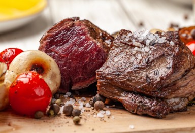 A juicy air fried steak rests on a cutting board with veggies