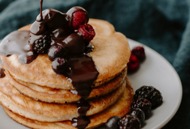 Stack of almond flour pancakes with chocolate drizzle and berries