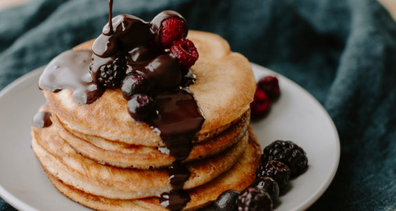 Stack of almond flour pancakes with chocolate drizzle and berries