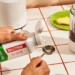 Hands measuring MCT oil next to a blending with coffee inside