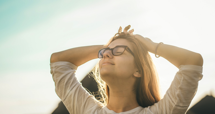 Woman with hands on head looking into sunshine