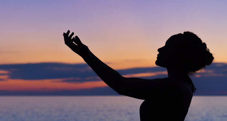 Woman holding hands out to sun