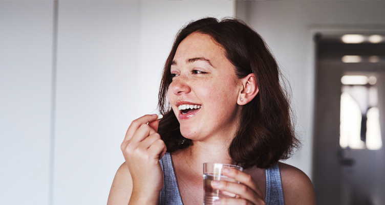 Woman taking pill and holding glass of water
