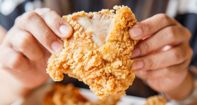 Person holding a piece of fried chicken
