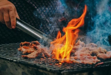 Person grilling meat with flare-up