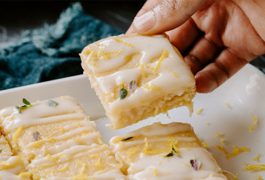 Hand grabbing paleo lemon drizzle cake slice