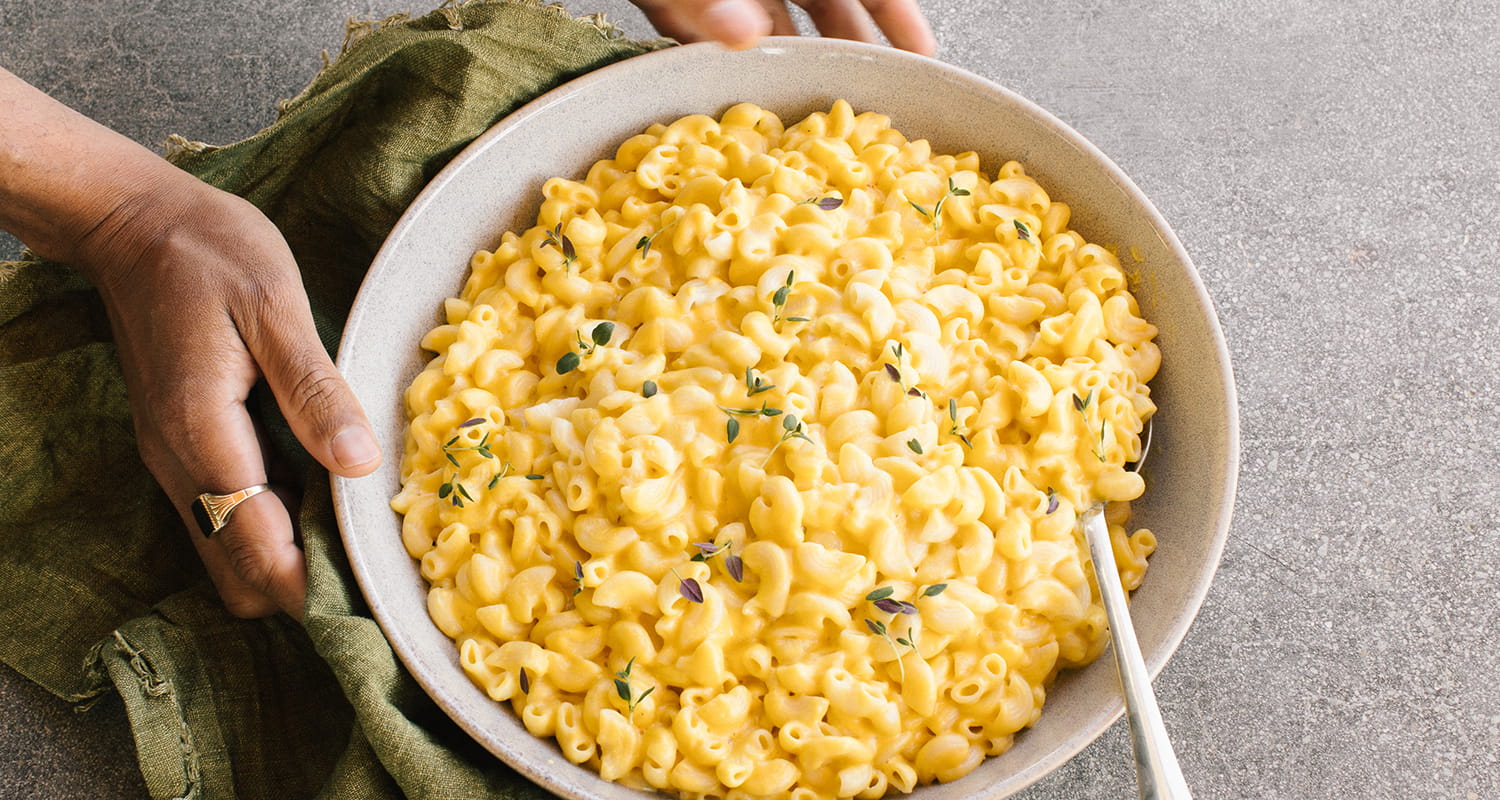 hands holding a large bowl of mac and cheese
