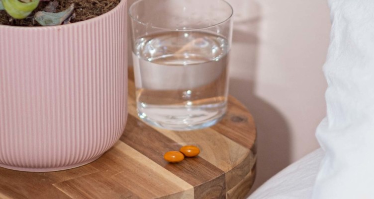 Bulletproof Sleep Mode tablets and a glass of water on a nightstand