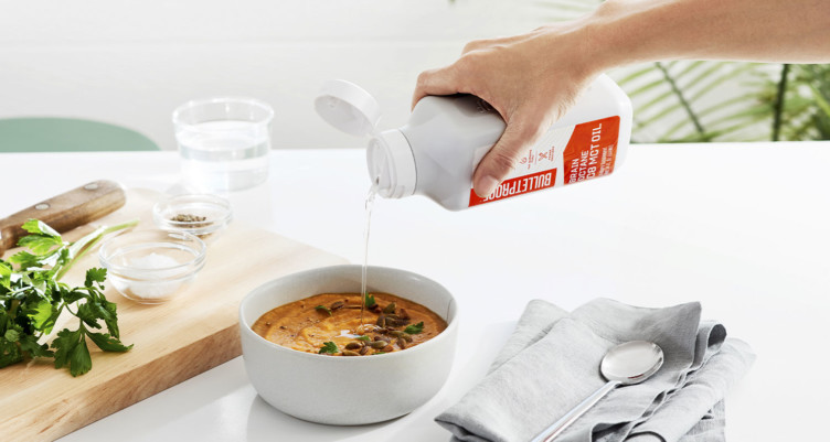 Person pouring Brain Octane C8 MCT Oil into soup