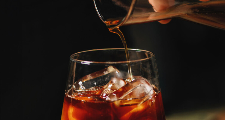 Cold brew coffee being poured into a glass of ice