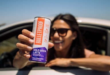 A woman in a car holding a can of Bulletproof Cold Brew Latte