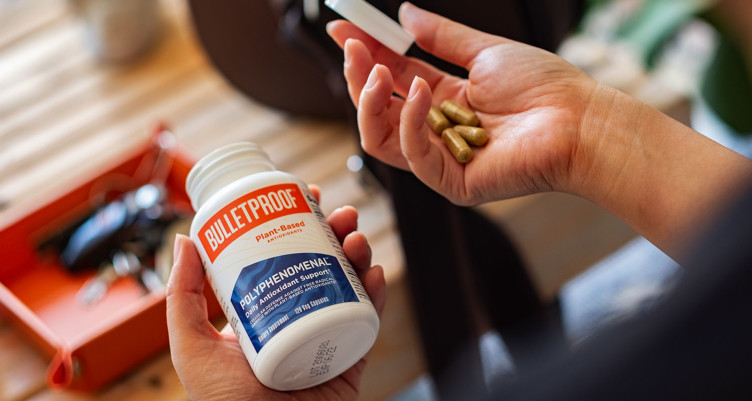 A bottle of Bulletproof Polyphenomenal supplements pouring into a hand