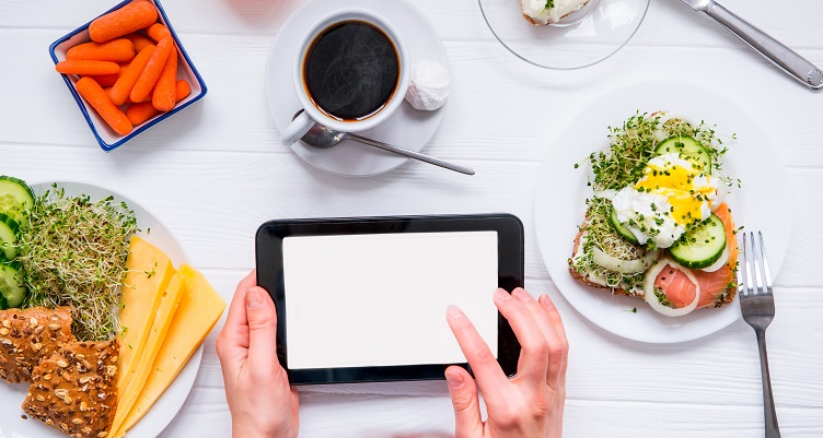 A person using a tablet at the breakfast table