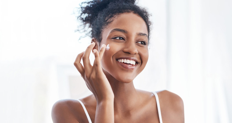 Woman putting face cream on cheek