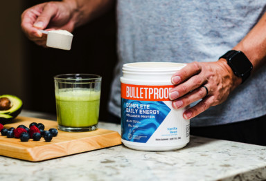 A person scooping Bulletproof Complete Daily Energy Collagen Protein into a smoothie