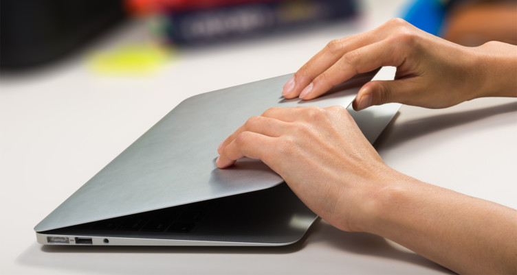 A person closing a silver laptop