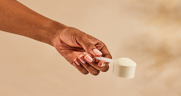 a hand holds a scoop of unflavored collagen peptides