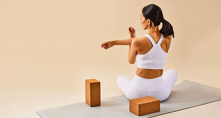 woman stretching on yoga mat with yoga block in matching activewear set