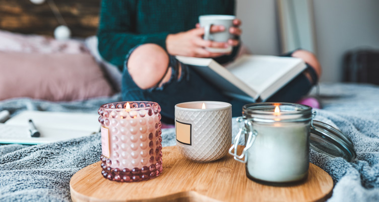 Woman reading with a cup of tea and candles