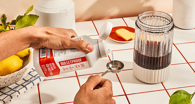 hands pouring Bulletproof Brain Octane oil into teaspoon measurement