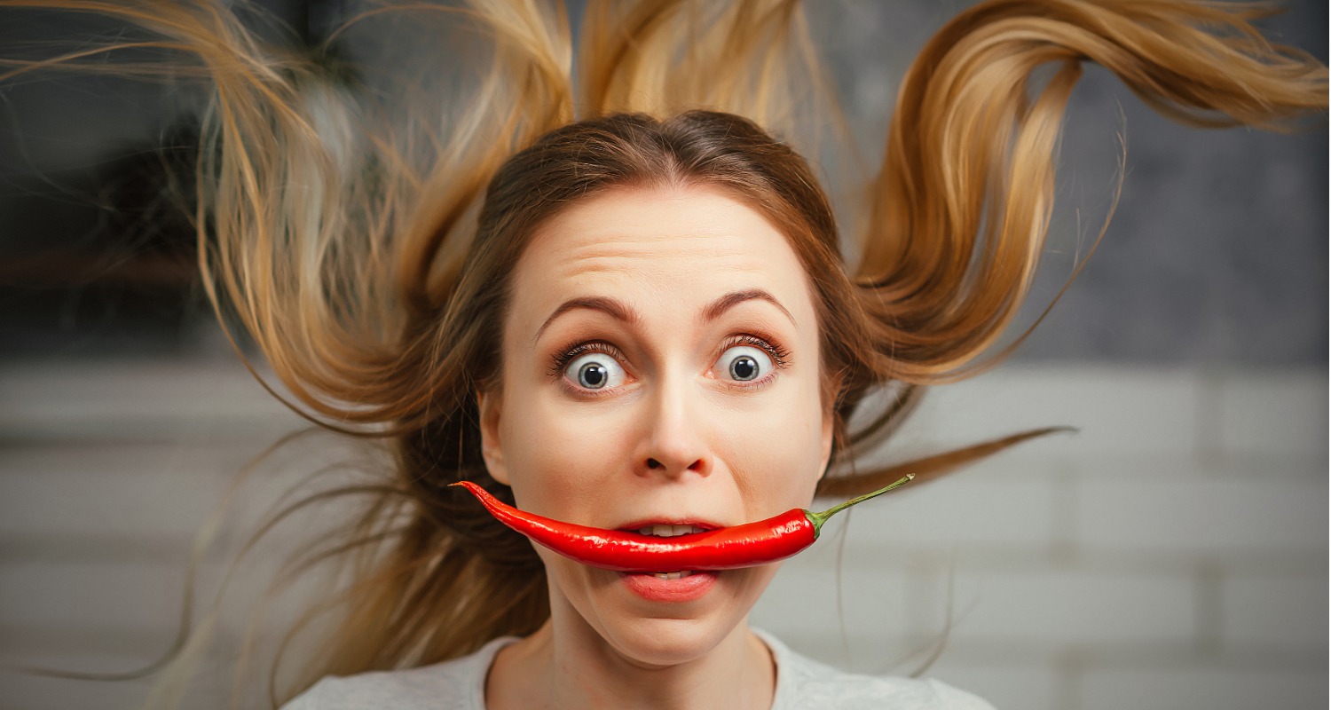 A woman with a hot pepper in her mouth
