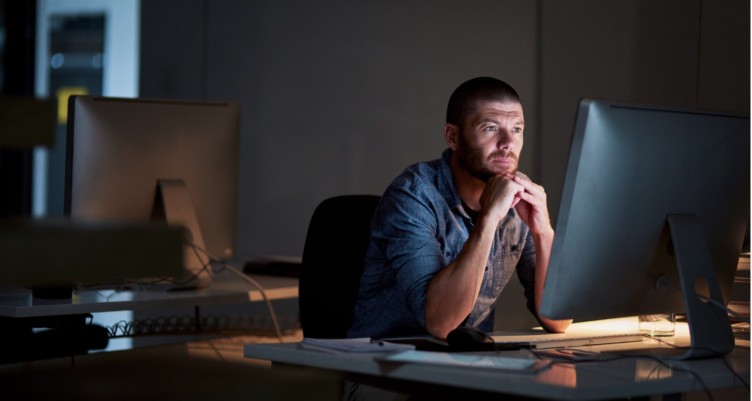 Man working behind a computer screen at night