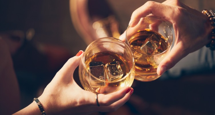 Two people toast with glasses of whiskey