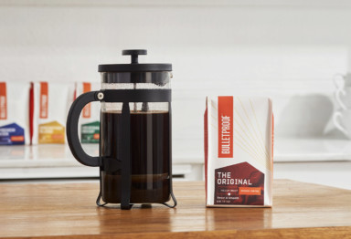 A French press and a bag of Bulletproof Original coffee