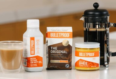 Bulleproof Ground Coffee, Brain Octane Oil & Ghee lined up sitting on kitchen counter next to coffee mug and a french press