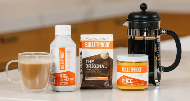Bulleproof Ground Coffee, Brain Octane Oil & Ghee lined up sitting on kitchen counter next to coffee mug and a french press