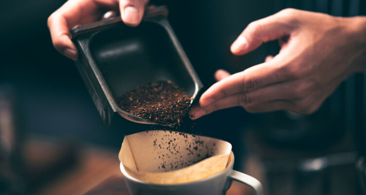 Hands pouring coffee grounds into a filter
