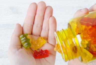 Person pours gummy vitamins from bottle into left hand.