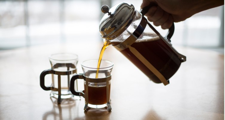 A French press pouring coffee into a mug