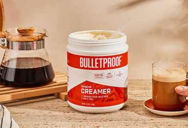 hand reaching for coffee with bulletproof original creamer next to it and a transparent coffee pot