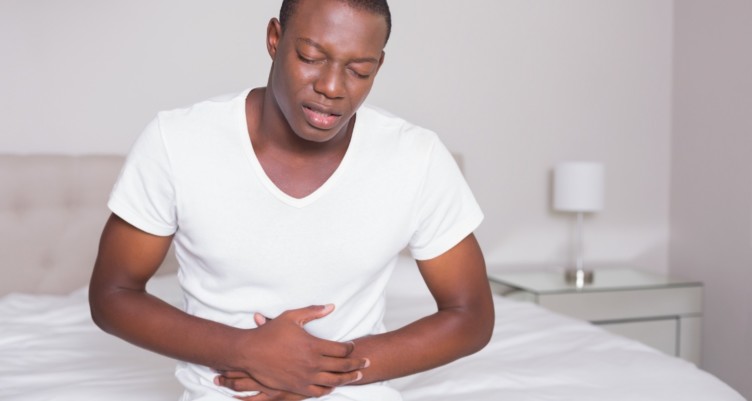 Man wincing at the end of the bed.