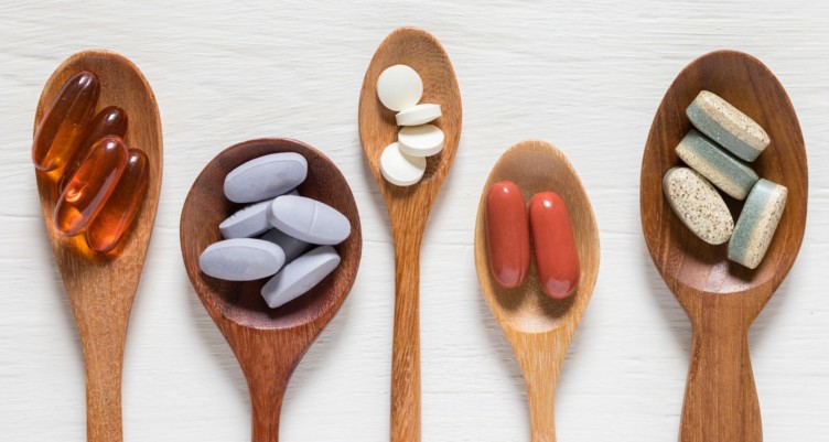 Wooden spoon filled with vitamins and supplements