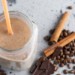 A mason jar of a coffee smoothie with cinnamon sticks
