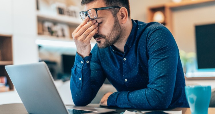 Man working on laptop reaching a point of exhaustion