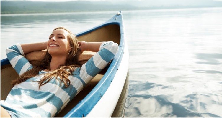 Woman laying in a boat by the ocean