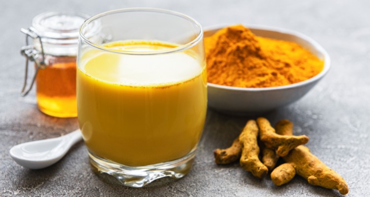 Glass of milk with bowl of turmeric