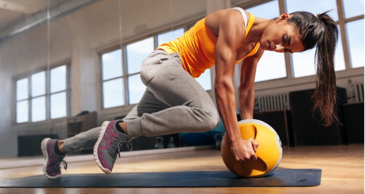 A woman in an orange tank top doing strength training exercises