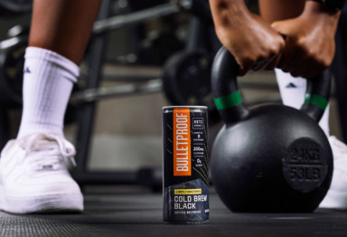 A person reaching for a kettlebell next to a can of Bulletproof Cold Brew Black