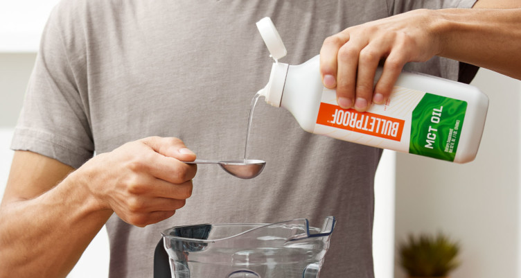 A person measuring Bulletproof MCT Oil to put in a blender