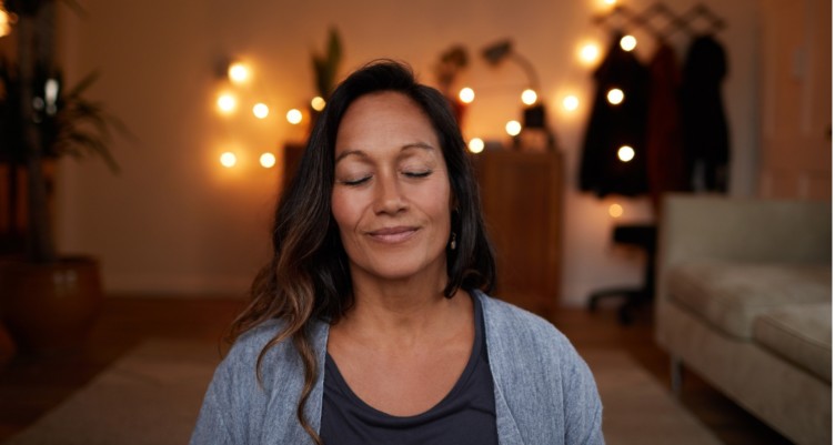 Woman smiling while meditating at home.