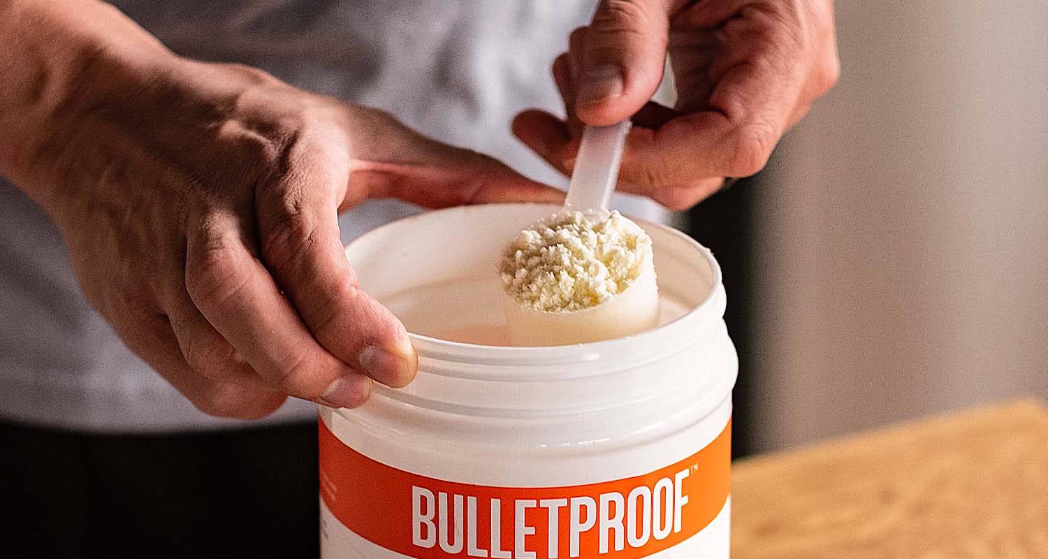 A hand scooping Bulletproof Creamer from a tub