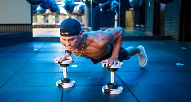 Fitness influencer Evan Betts doing pushups on top of dumbbells.