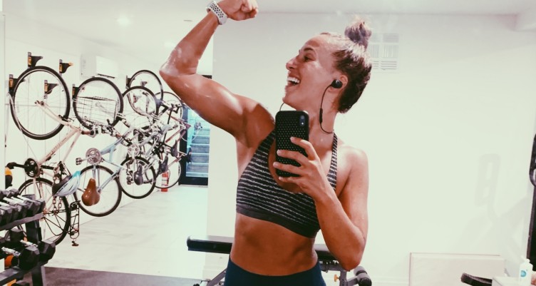Fitness influencer Mary Wolff flexes her right arm for the camera.