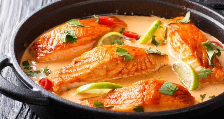 Fillets of salmon in pan of spicy Thai coconut sauce