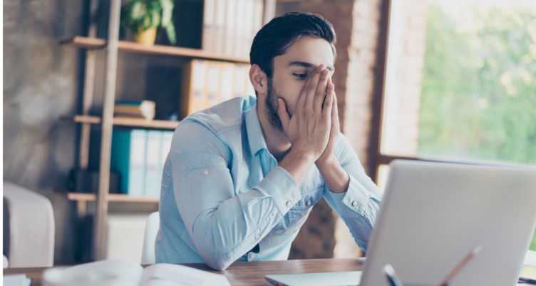 Man working on computer holding his face in frustration