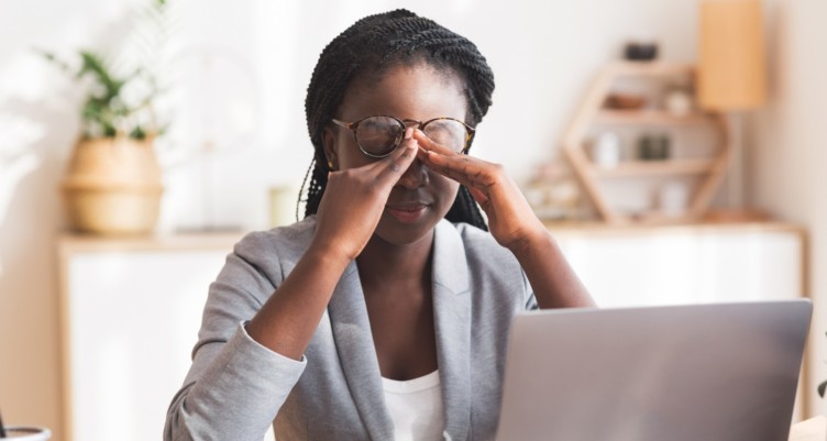 Woman feeling fatigued while working on her laptop.